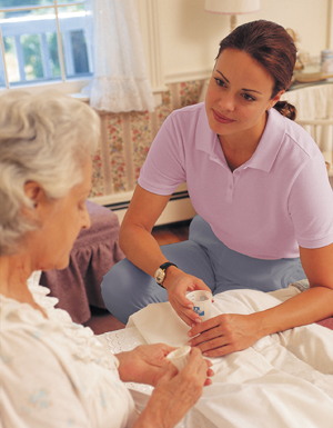 Woman giving medication in cup to older woman in bed.